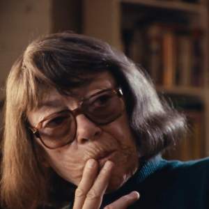 In a still from a film made in 1992, Joan Mitchell looks away from the camera with her hand over her mouth.