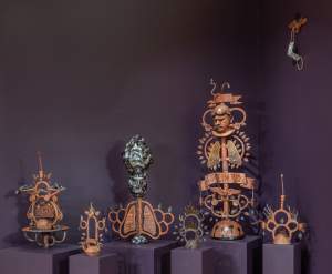 El árbol del medio ambiente en la villita is a group of variously sized brown devotional sculptures standing on plinths, with elements of leaves, lungs and flames in symmetry.