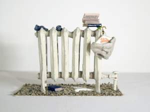 Untitled (Ahh Life) is a miniature sculpture of a white radiator, with 2 tiny books on top, drying socks, and underwear hanging from a wire and paper hanger reading Liberto cleaners.