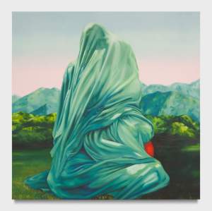 A figure draped in green fabric sits in a grassy landscape with mountains in the background, holding a red object.