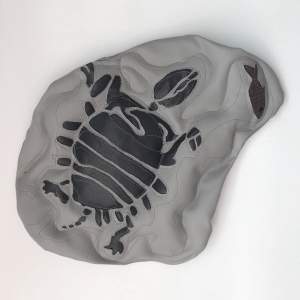 Sewn vinyl mimicking a stone fossil, with the outline of a turtle and a fish.