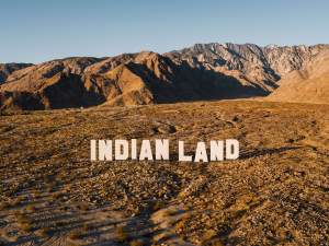 “Never Forget” is a sculptural installation in a desert scrub expanse, of large letters reading “INDIAN LAND” in the same style as the famous Hollywood sign.