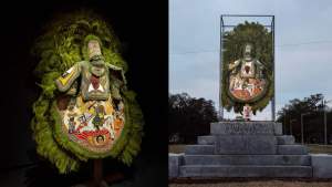 “Jah Defender” is a opulently decorated green feathered suit with beaded apron plate, featuring a Nyabinghi warrior on horseback above the Ethiopian icon of Saint George, flanked on either side by Empress Menan and Haile Selassie. The chest plate features a large portrait of the deceased roots reggae artist, Aeke Beka. On the right, the suit is displayed in a clear box on the pedestal of a former Confederate monument.