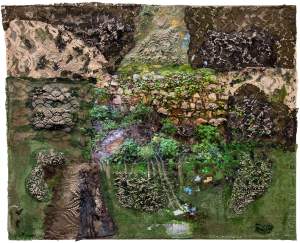 “Soft Power” is a rectangular altered photograph of a stone wall with vegetation growing in between the stones. The surface is covered in various places with black and beige lace, painted green in areas, and cement pushes through the fine holes of the lace in areas, echoing the stone textures of the partially visible photograph.