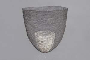 Floating in a gray space, “The Offering Bowl 07” is a deep transparent bowl of finely woven black hair. Sitting inside is a smaller cup of finely woven white hair.