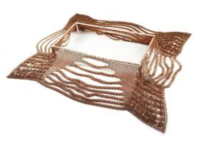 An Unwelcome is a sculpture made of very fine filigree copper chainmail extending from a square center form in variable linear and grid patterns forming a loose square frame.