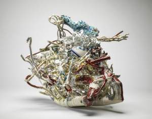 Spill is an abstract ceramic sculpture with a curved bottom, covered with thin forms of ceramic tangles in white red, blue and tans, with embedded fragments of Dutch blue and white pottery.