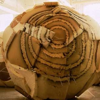 A large sphere  made of a patchwork of beige-brown upholstery foam, with an overlaid textured bullseye