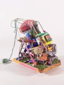 Perseus and Andromeda (After Tiepolo) is a colorful abstract sculpture featuring various materials like wire, wood, and fabric, arranged in a complex, layered triangle pile on a wooden base.