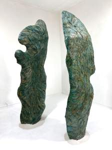 The sculpture Camera Revelatorium consists of two biomorphic green columns standing in a white room, with an undulating form and texture.