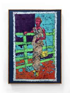 Dora is a colorful batik artwork of a person in a striped dress, holding a yellow bag, standing by a green fence against a blue and purple background.
