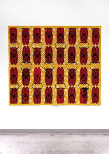 Seventeen Years is a large textile artwork featuring multiple rows of red and black cicadas patterned on a yellow background, displayed on a plain white wall.