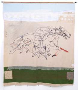 Racing is a textile artwork depicting an outline of a jockey riding a galloping horse, its motion captured in overlapping layers, stitched on fabric with a grassy green strip below and a blue sky above.