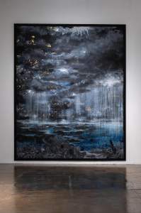 A Mothers Prayer: A Son’s Anxiety is a large vertical abstract painting depicting a dark, cloudy sky with gold flecks over a blue and black landscape, with streaks resembling rain. A reflection is visible on the polished floor.