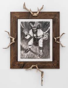 Framed artwork with antlers affixed on each side, featuring a person crouching with hands outstretched.