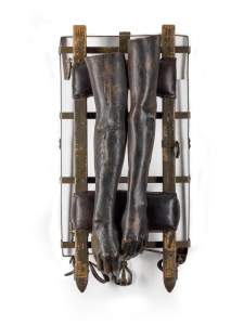 Without you is a bronze sculpture of two disembodied arms draped over an medical stretcher-like form with dark leather pads, wood planks, and metal hardware.