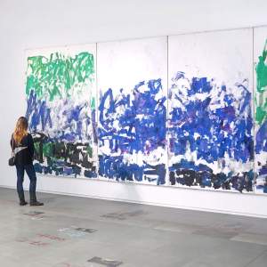 A person stands in front of a Joan Mitchell abstract quadriptych in energetic blues.