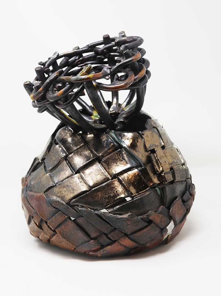 A ceramic sculpture made from sections of clay woven together and finished with a bronze-toned metallic glaze.