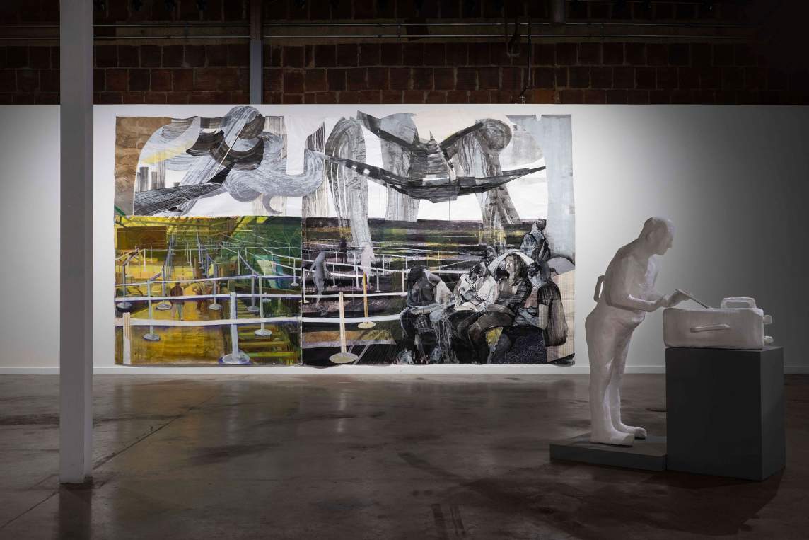 In the foreground, “Suitcase” is a white plaster person with a handle on their back, leaning forward to open a white suitcase on a plinth. In the background is “In Between the Lines”, a large painting with a group of figures sitting and huddled together at the bottom right corner, and beyond them a labyrinth of line stations. Above the scene are undulating swirls and airplane wings.
