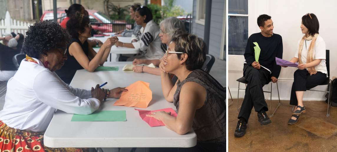 On left, at a long table on a patio, pairs of people sit across from each other in discussion with pieces of colored paper with writing on them. On right, Anthony White, a multiracial man wearing black, and Sammy Seung-min Lee, a woman of Korean descent with straight black hair wearing a white shirt and tan scarf, sit next to each other in chairs, smiling in discussion.