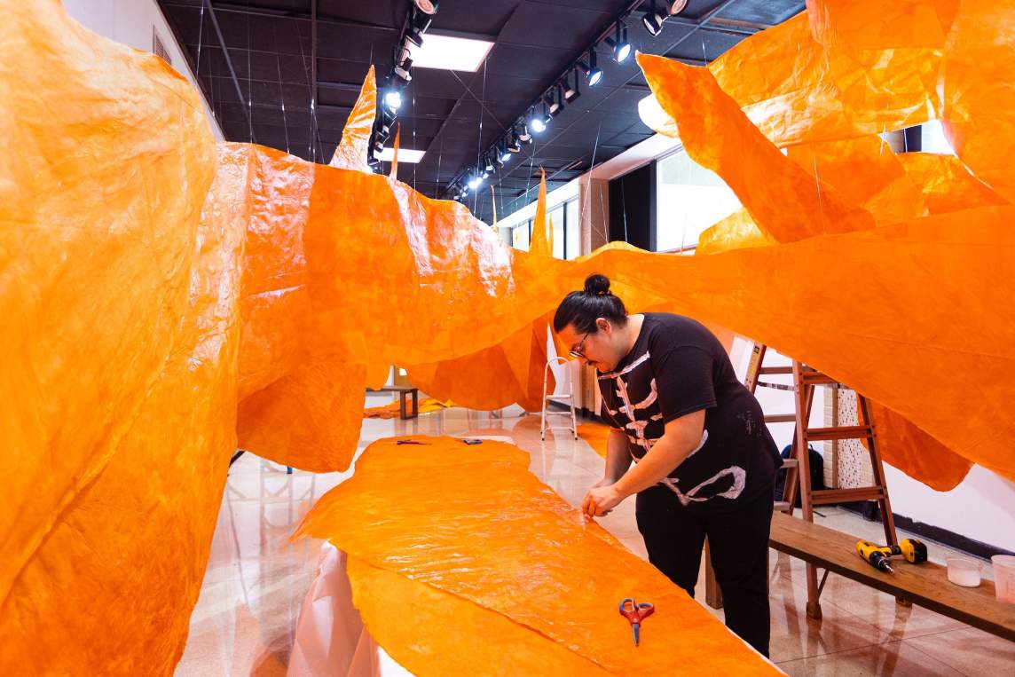 Justin Favela surrounded by orange paper pieces