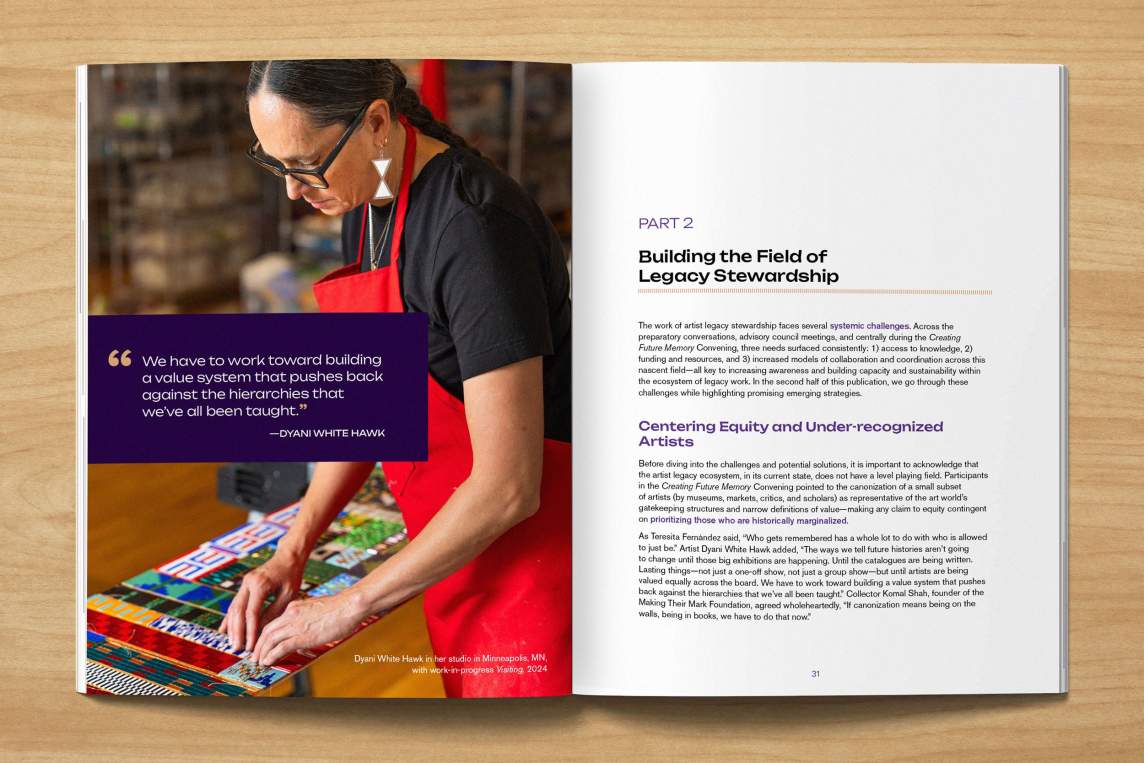An open book on a light wood grain table. On the left page is a photo of artist Dyani White Hawk, an artist of Sicangu Lakota, German, and Welsh ancestry. She has long hair and a bright red apron, and is arranging beads on a complex geometric artwork. Text on the right page begins "Building the Field of Legacy Stewardship."