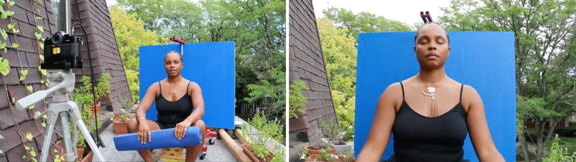 Ash Arder, a Black woman with medium-dark skin tone, sits on a patio in front of a blue panel, facing a video camera that records her while she sits and a shea butter necklace melts on her skin.