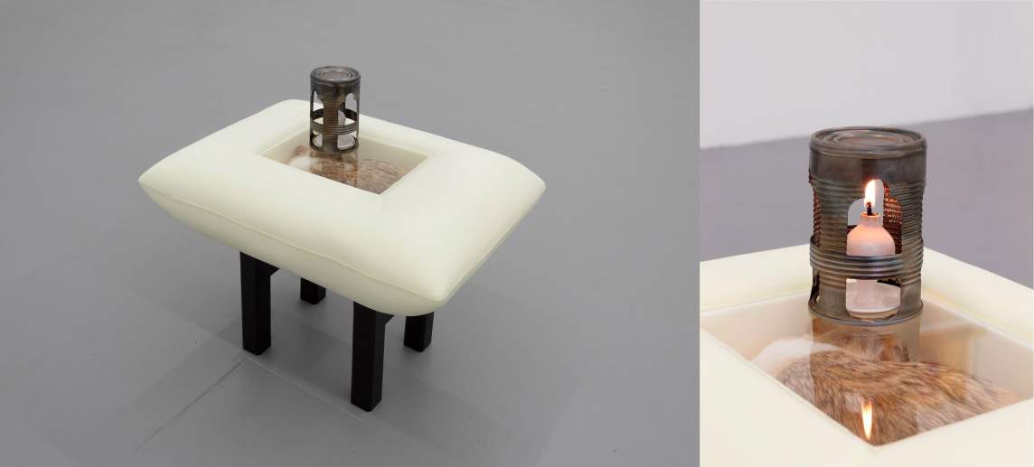 The cat in my brain is walking is a sculpture of a sleeping cat sealed in a pillowed vitrine. The table-like structure holds a single cast porcelain oil lamp, lit beneath an ornately cut metal can.