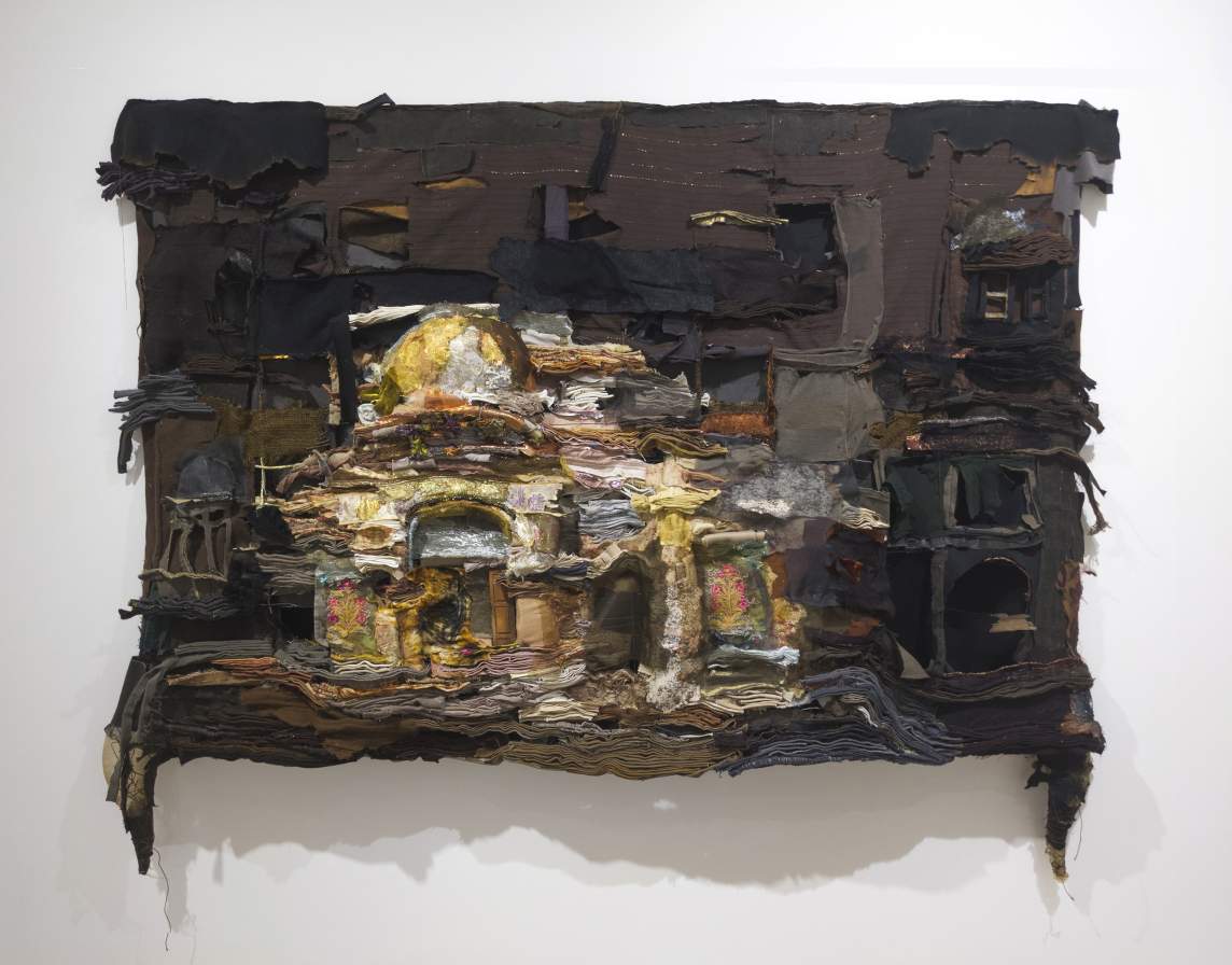 Stratigraphy Of Cloth is a mixed-media artwork composed from stacked and layered fabric and textured materials. The layers of materials in different colors come together to form a domed building on a dark background.