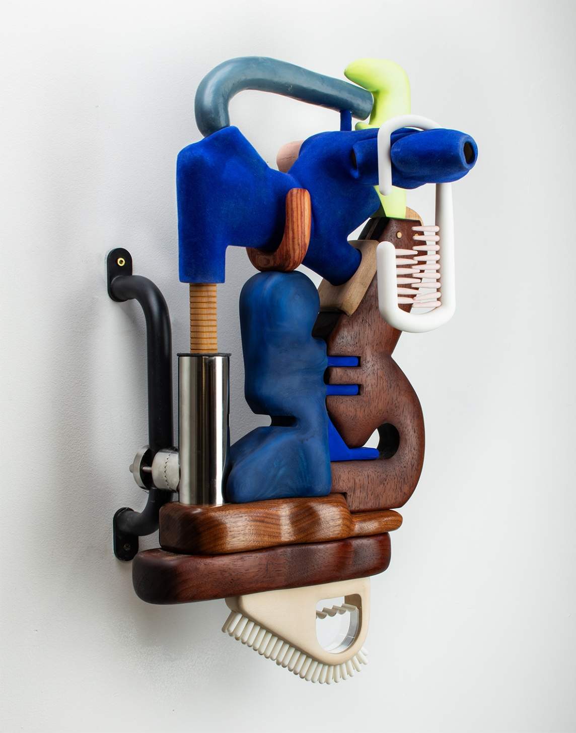 Trolling (blue raz) is a wall sculpture composed of interlocking wooden forms in biomorphic shapes, with metal hardware elements including a silver tube and a black pull bar.