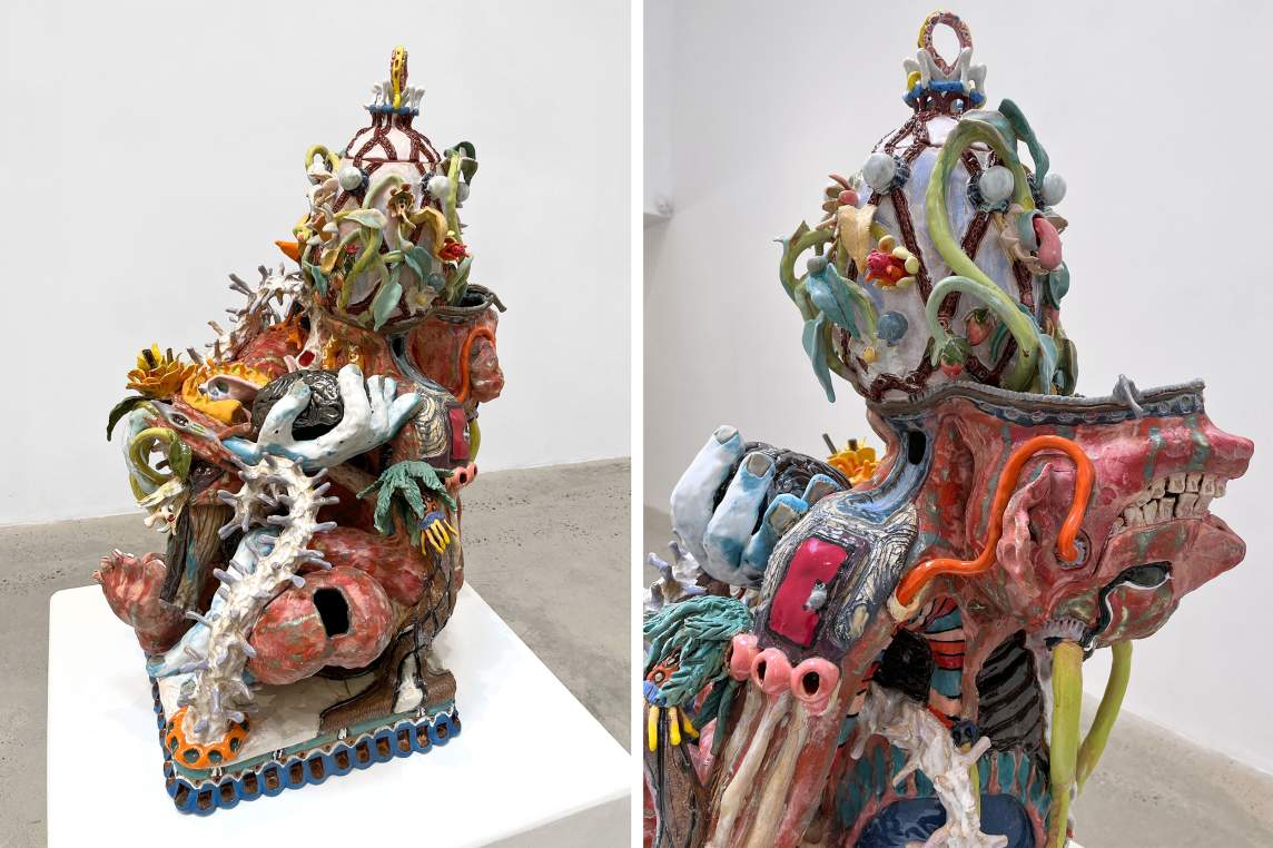 Colorful ceramic sculpture with intricate details forming a complex, multi-layered figure, setting partially crosslegged with a Faberge egg as a head, and demon like mask folded backwards over the shoulders.