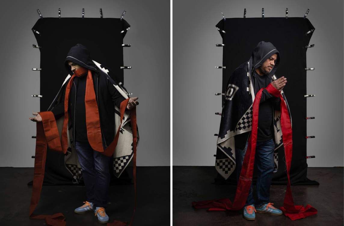 Left: In Mourning the Motherland (Praying) the artist stands in front of a clamped black backdrop with outstretched open hands and bent head. He wears a patterned cloak, black hood, and a strip of red fabric covers his mouth and drapes down his lapels and over his hands. Right: In Mourning the Motherland (Pleading), the artist stands in front of a clamped black backdrop with hands together in prayer. He wears a patterned cloak and black hood and looks down towards his hands.