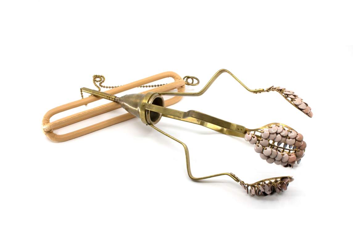 Body Weaponized No. 8 is a sculptural object resembling a tool of uncertain purpose. 4 radial arms of bent metal extend from a center cup, each with a mesh spoon covered with enameled disc beads.