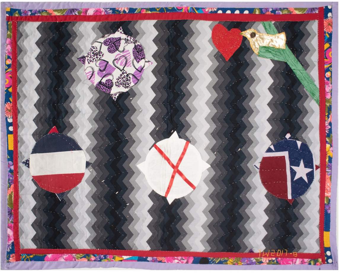 Bird + 3 Flags is an embroidered quilt with a geometric grayscale background and four orb shapes, each with four points and different patterned backgrounds. At the top left, a bird perched in a tree branch holds a heart in its mouth.