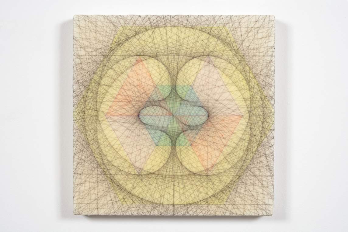Empty Void 37, an abstract square artwork, hangs on a white wall. The composition includes geometric and organic shapes that radiate outward from the center, with light yellow and rainbow tones. The piece is criss-crossed throughout by strands of the artist’s black hair, which create a visual net over the composition.