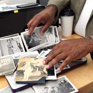 Hands of artist Gus Bennett sorting through black and white family photographs