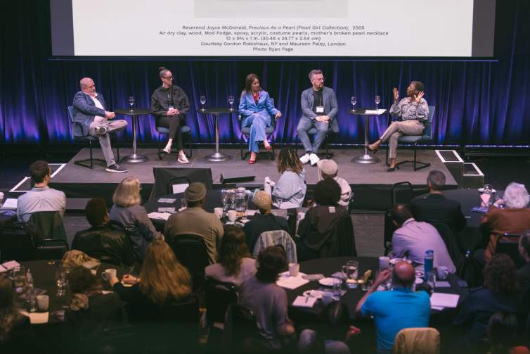 Five people of different ages and ethnicities sit on a stage for a panel discussion.