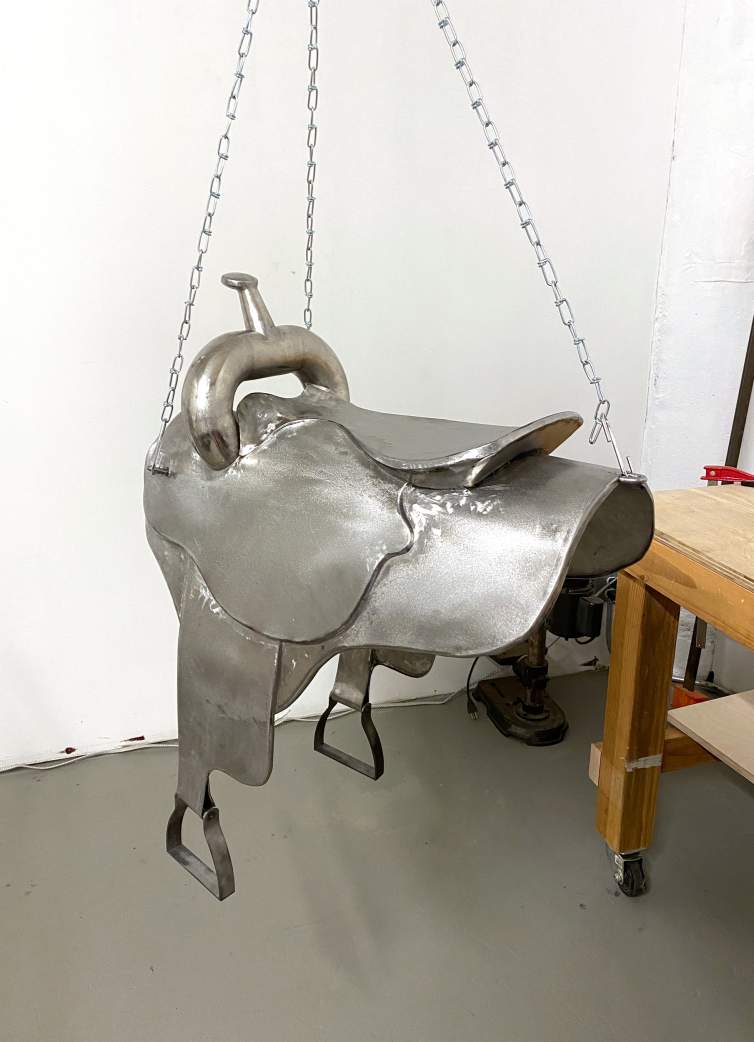A metal replica of a horse saddle hangs from a chain in Peggy Chiang's studio.