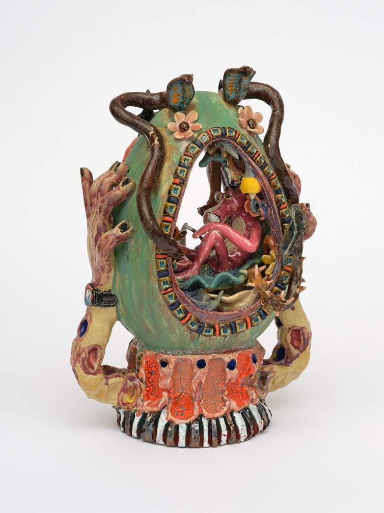 Garden Egg is a surreal ceramic sculpture with the figure of the Pink Panther seated inside a floral, oval egg with surrounding hands, tentacles, and intricate, colorful designs on a green and orange base.