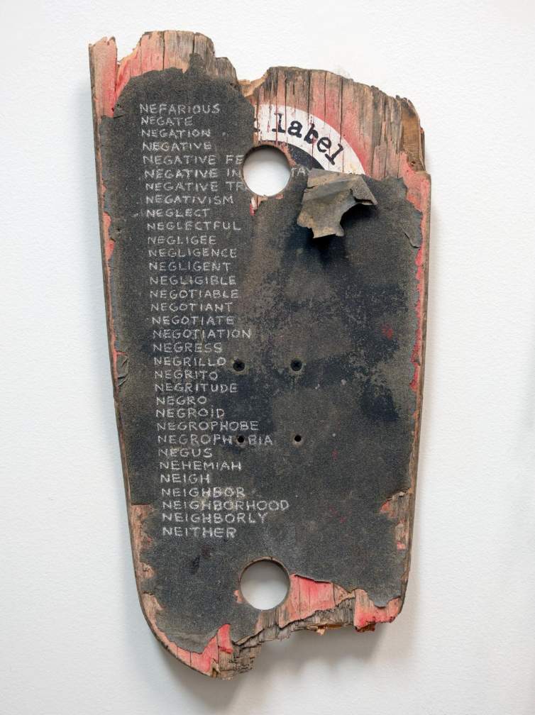 On a battered skateboard deck, around 30 words that start with NE are written in white chalk. beginning with NEFARIOUS, NEGATE, NEGATION, NEGATIVE... and ending with "NEIGH, NEIGHBOR, NEIGHBORHOOD, NEIGHBORLY, NEITHER.