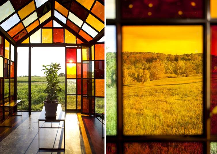 A composite photo of two details of William Lamson's Solarium, a greenhouse-like sculpture set on a grassy hill, formed of gridded panes of yellow, brown, and honey colored glass. At left, we see an interior of Solarium with small trees growing on a table and grass fields visible outside. On right, we peer through a yellow-tinted glass pane to the rolling hills, trees, and sky outside.