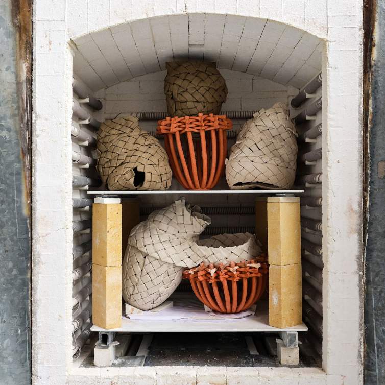 An array of intricate ceramic pieces packed inside a kiln, ready for the firing process.