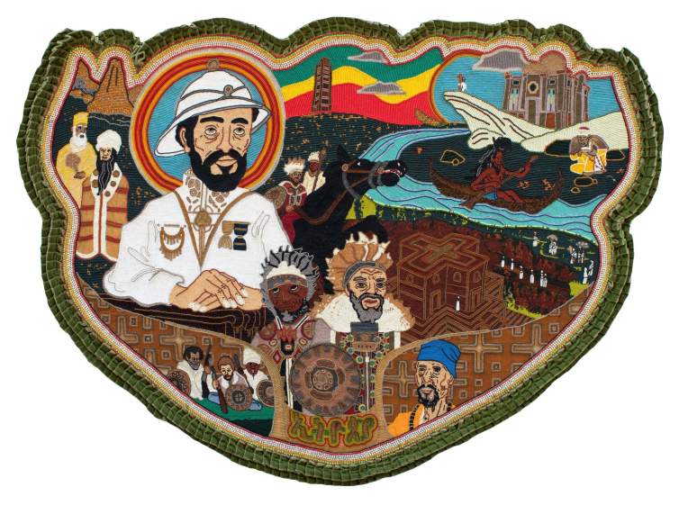 “Ethiopia” is a large beaded apron medallion centered on a depiction of Haile Selassie, the former Emperor of Ethiopia in white military suit with folded hands and a white pith helmet. He is surrounded by other motifs including Nyabinghi warriors, a rock-hewn church in Lalibela, Ethiopian hermit monks, and the Obelisk of Axum. The apron is bordered in a velvet green ruffle.