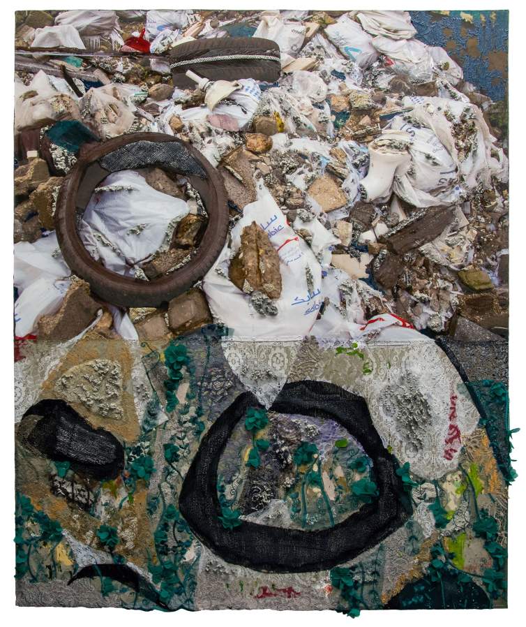 Wheels of Fortune is a rectangular mixed-media artwork. At the top of the composition is a photograph of a pile of household and industrial debris, including pillow cases, bits of brick, and old tires. The artist has continued the photograph’s composition in the bottom section with painted and applied elements, using lace, cements, and acrylic paint.