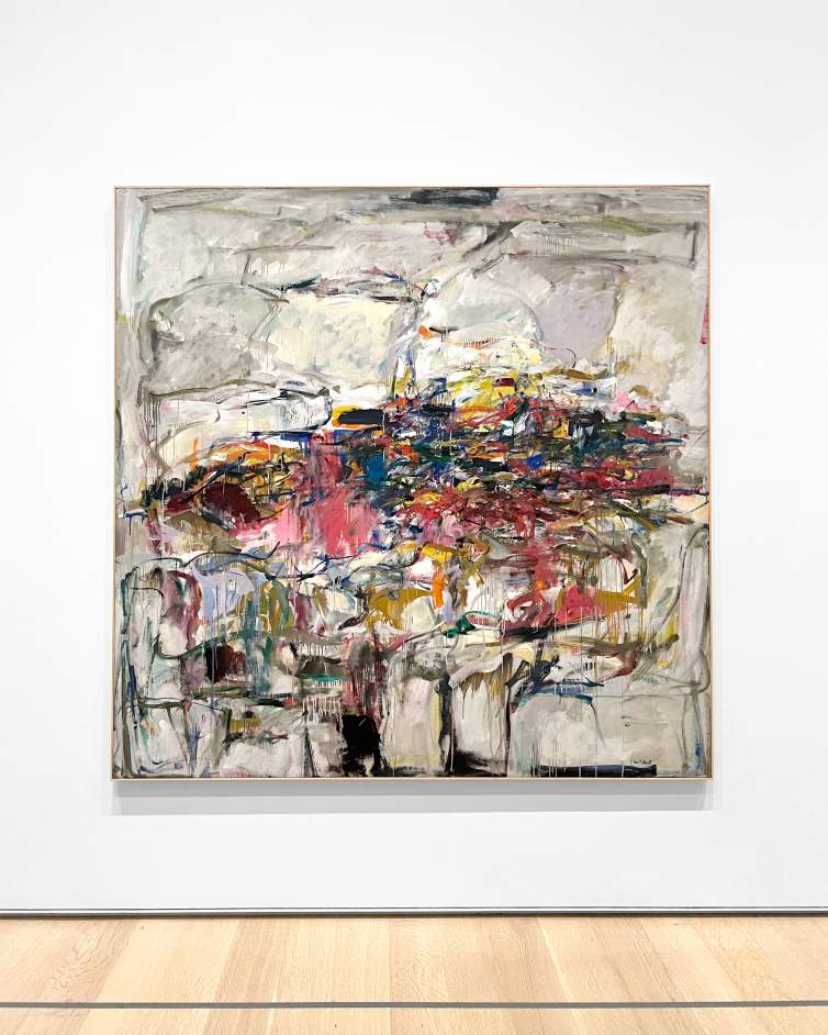 City Landscape is an abstract painting composed of a central tangle of vibrant colors—purple, pink, orange, green, red—on a mostly gray background, subtly divided into rectangular areas. It is shown hanging on a white gallery wall over a wooden floor.