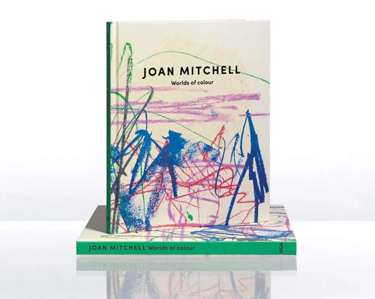 A book titled "Joan Mitchell: Worlds of Colour," stands upright with an abstract, colorful cover with bright gestural pastel marks.