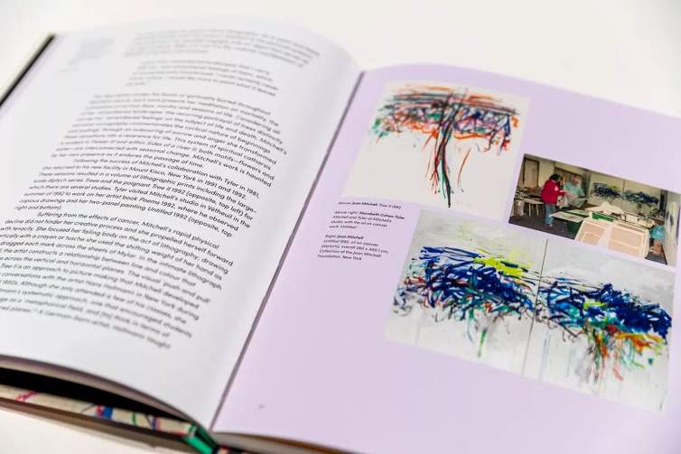 A spread from the book "Joan Mitchell: Worlds of Colour” with an essay on one page, and images of abstract artworks and a photo of Joan Mitchell working in a print shop on the other page.