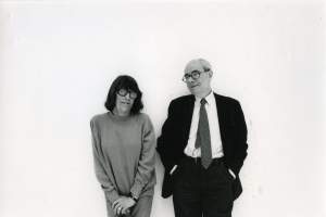 An older Joan Mitchell stands with hands clasped on a cane, next to Jean Fournier, and older balding white man with glasses and a suit, his hands in pockets