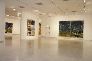 Several large abstract paintings by Joan Mitchell hanging in a white gallery