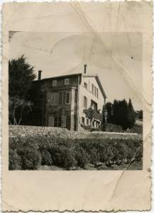 A picturesque French country house with shutters bordered by a stone wall